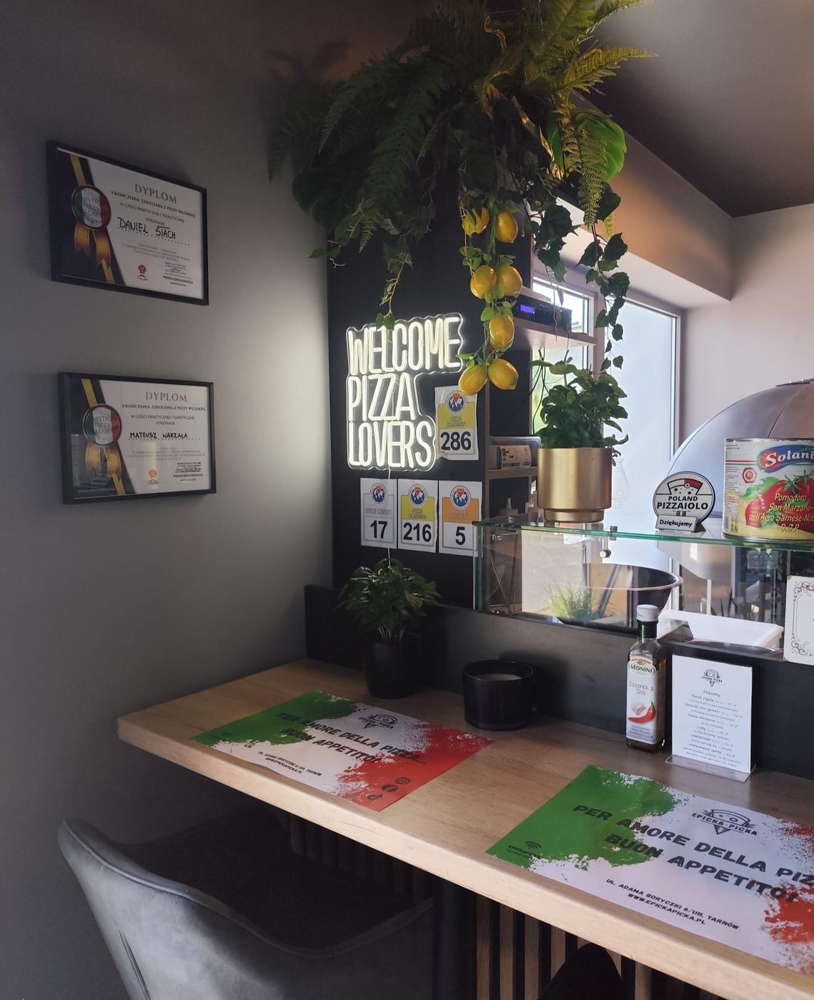 Kącik z neonem „Welcome pizza lovers” i dyplomami pizzaiolo